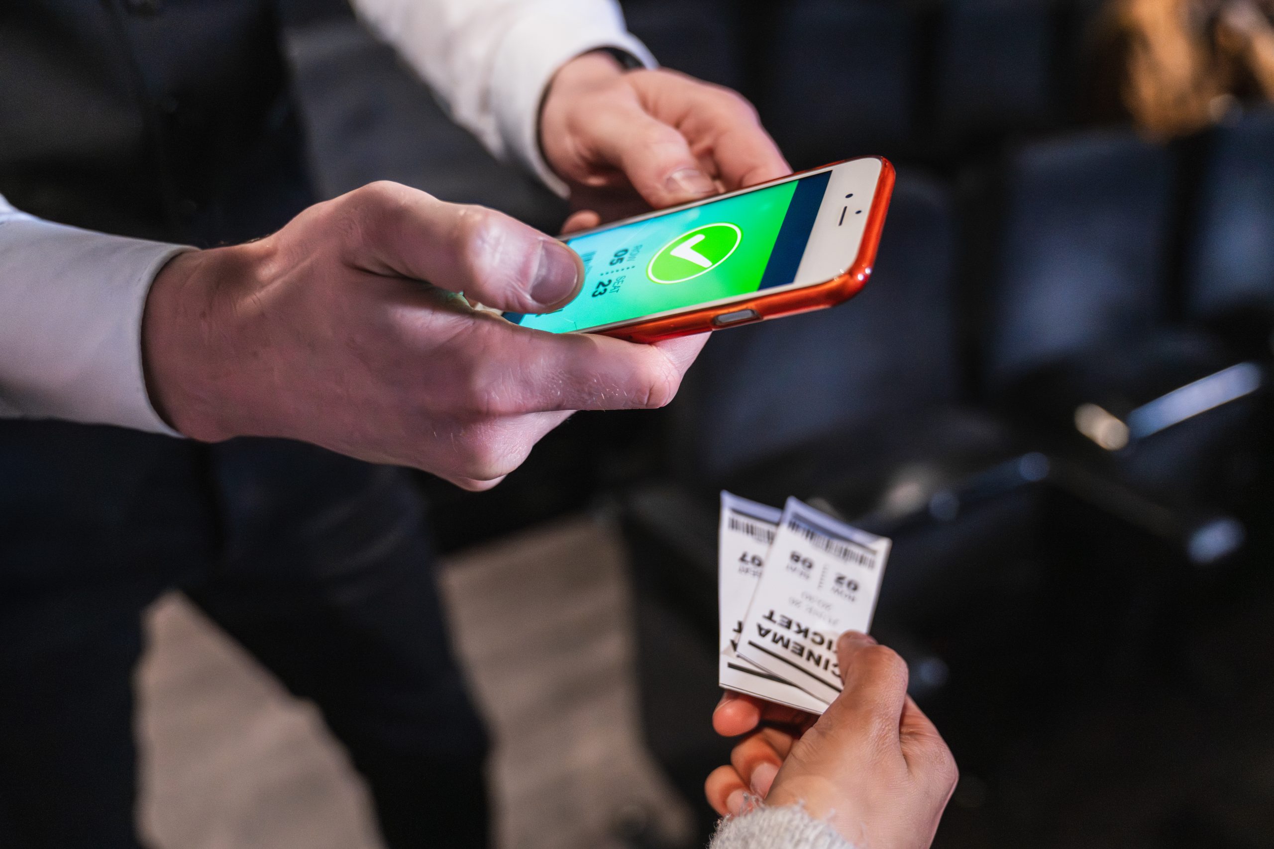 Usher checking digital ticket on smartphone in cinema theatre